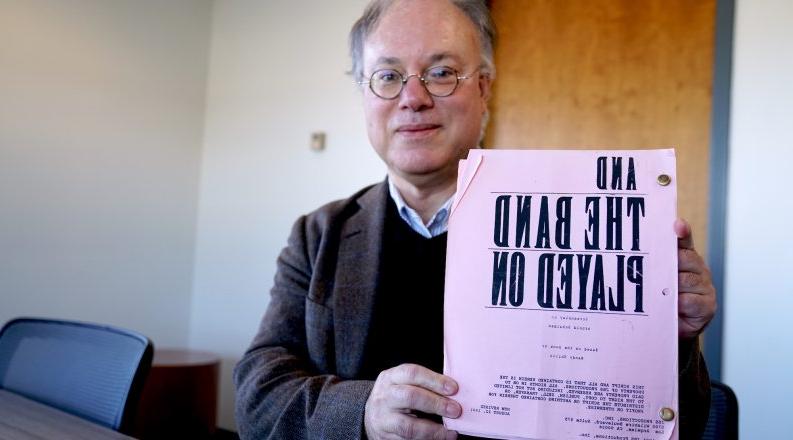 A man holds up a film script. 